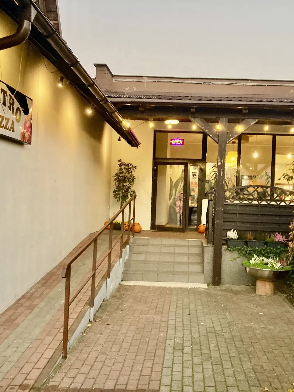 Wejście do Bistro Pizza z podświetlonym szyldem